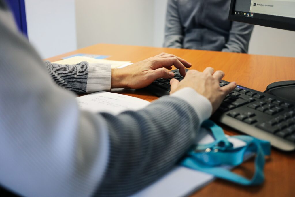 conseiller mission locale qui aide un jeune dans des démarches administratives. IL tape sur son clavier d'ordinateur